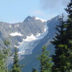 A mountain with snow on it and trees in the foreground.