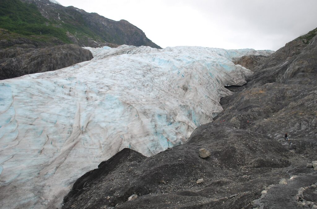 A large white glacier is on the side of a mountain.