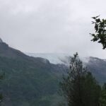 A view of the mountains from the side of a hill.