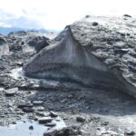 A rock formation with water and rocks in the background.