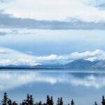 A body of water with trees and mountains in the background.