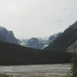 A view of mountains and water from the side of a road.