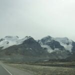 A road with snow covered mountains in the background.