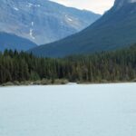 A lake with trees and mountains in the background