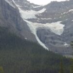 A mountain with snow on it and trees in the foreground.