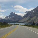 A road with mountains in the background and water