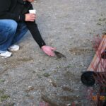 A person holding something in their hand near an open fire pit.