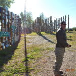 A man standing in front of many wooden posts.